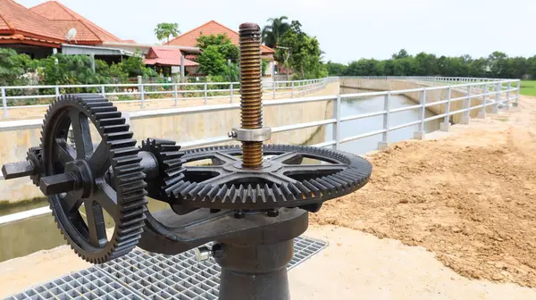 Dam dişli sistemi. Sulama kanalının kenarındaki su kapısının açılıp kapandığı ve fotokopi alanı olan kentsel bir topluluğun içinden aktığı çarkların yakınlaştırılması. seçici odak