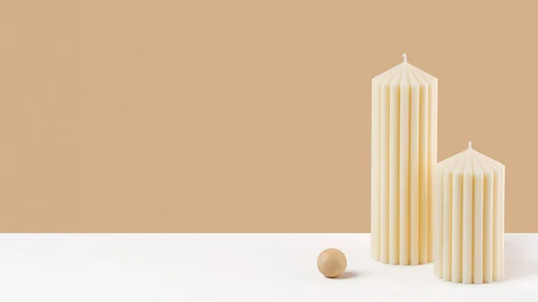 Handmade olive wax pillar candle on a neutral pastel and white background. Sustainability vegan candle, natural materials. Minimalistic, cozy atmosphere modern photo. Copy space. Banner.