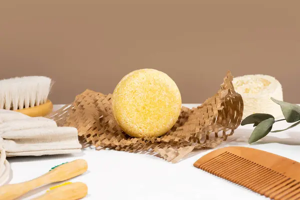 Eco friendly solid shampoo bar on a Honeycomb Paper and natural materials bathroom accessories lying on a white and brown background. Plastic free, zero waste, low water ingredients. Copy space.