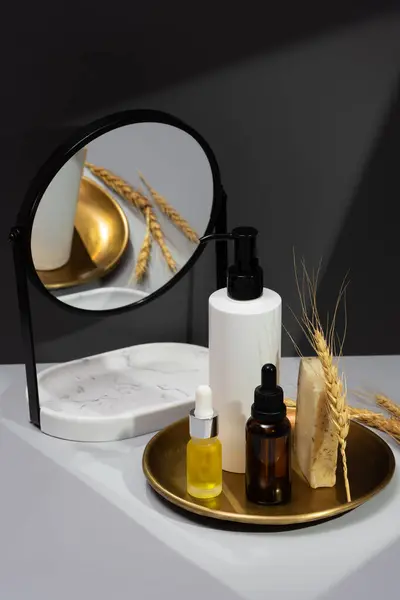Set of essential oils, handmade soap and mirror on a dark gray background. Creative still life with organic cosmetics. The concept of selfcare and organic products. Reflection in the mirror.