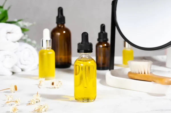 A set of organic cosmetics in glass bottles with dropper for skin and hair care. Natural oils and dried flowers on the cosmetic table in the bathroom. The concept of home care in the bathroom.