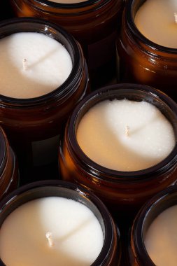 Kahverengi cam kavanozlarda farklı aromalı soya ve hindistan cevizi mumları. Kokulu el yapımı mum. Kehribar kavanozundaki doğal mumlar. Aromaterapi ve spa 'da ve evde rahatlamak. Kapatın. Makro. Dikey.