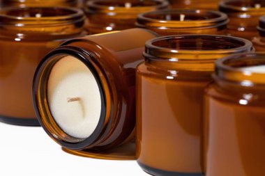 Kahverengi cam kavanozlarda farklı aromalı soya ve hindistan cevizi mumları. Kokulu sakinleştirici mum. Kehribar kavanozundaki doğal mumlar. Aromaterapi, sağlık ve kaplıca ürünlerinde rahatlama. Kapat..