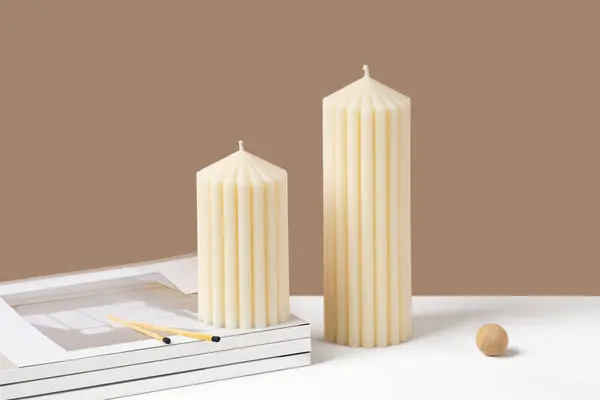 Handmade olive wax pillar candle on a neutral beige and white background. Sustainability vegan candle, natural materials. Minimalistic, cozy atmosphere modern still life photo. Copy space