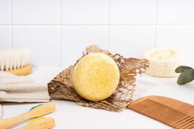 Çevre dostu sağlam şampuan barı ve banyodaki spa aksesuarları. Plastiksiz, sıfır atık, düşük su içerikli. Beyaz seramik zemin üzerinde kompozisyon. Sürdürülebilir saç bakımı.