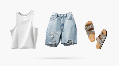 Havalı uçan pamuklu bluz, mavi kot şort, gri arka planda izole edilmiş vegan mantar sandaletler. Temiz, beyaz bir bluz. Marka kıyafetleri. Tasarımın için hazırlan. Bahar Yaz Kadın Giysileri.