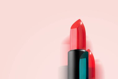 Açık pembe arka planda siyah tüpte parlak kırmızı ruj. Lüks dekoratif kozmetik. Yaratıcı arıza stili. Yatay olarak. Boşluğu kopyala.