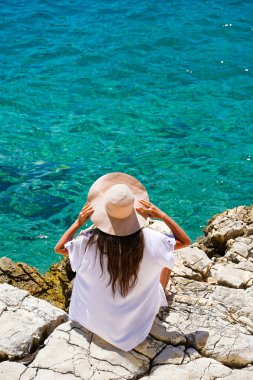 Hasır şapkalı çekici kadın güzel turkuaz denize bakıyor.