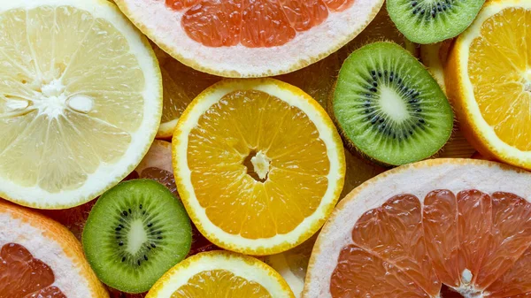 Top view of citrus fruits cut into slices on wooden background