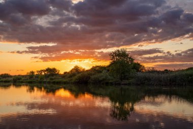 İnanılmaz manzara, dramatik gökyüzü günbatımı küçük göl kenarında.