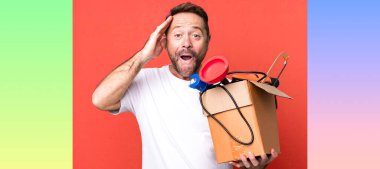 Orta yaşlı adam mutlu, şaşkın ve şaşırmış görünüyor. Alet çantası olan bir tamirci.