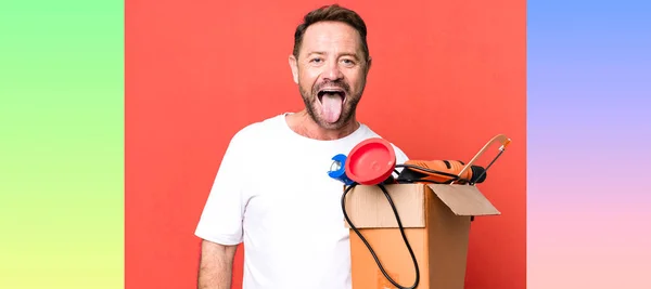 陽気で反抗的な態度を持つ中年の男冗談と舌を突き出す 道具箱付きの便利屋 — ストック写真