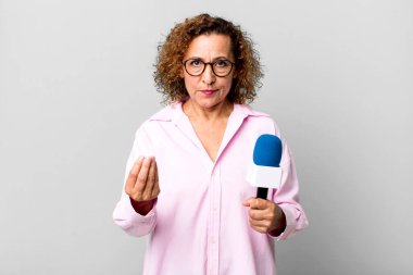 Güzel orta yaşlı bir kadın kapiş ya da para hareketi yapıyor, sana ödemeni söylüyor. Mikrofon konsepti olan bir TV sunucusu