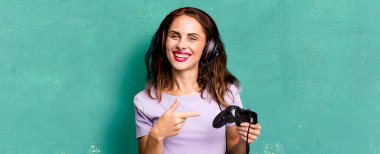 hispanic pretty woman smiling cheerfully, feeling happy and pointing to the side. gamer concept