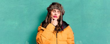 hispanic pretty woman thinking, feeling doubtful and confused. wearing an anorak. cold and winter concept
