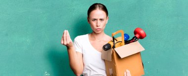 caucasian pretty woman making capice or money gesture, telling you to pay with a tool box. repair home concept