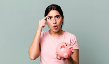 looking surprised, realizing a new thought, idea or concept. with a piggy bank