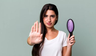 looking serious showing open palm making stop gesture. hair comb concept