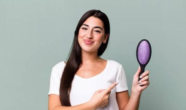 smiling cheerfully, feeling happy and pointing to the side. hair comb concept