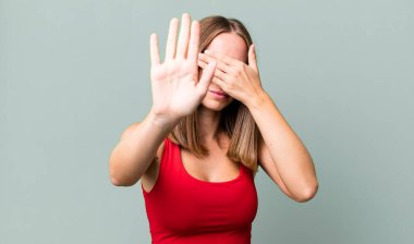 Yüzünü eliyle kapatıyor ve kamerayı durdurmak için diğer elini öne koyuyor, fotoğraf ya da resimleri reddediyor.