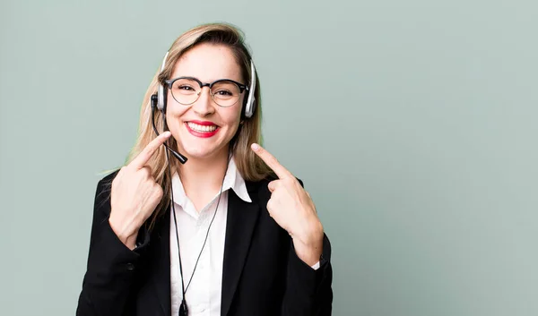 smiling confidently pointing to own broad smile. telemarketer concept