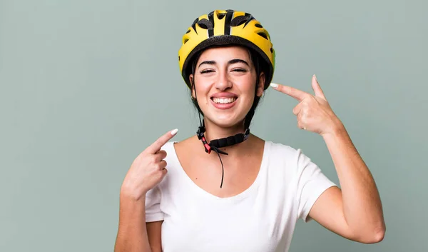 smiling confidently pointing to own broad smile. bike helmet concept