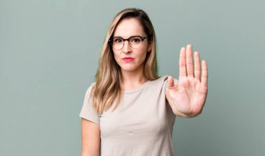 Ciddi, sert, hoşnutsuz ve kızgın görünüyor. Avuç içini açıp, jestleri durduruyor.