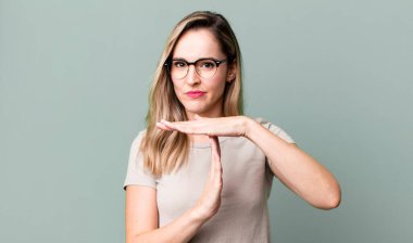 Ciddi görünüyor, sert, kızgın ve hoşnutsuz, mola işareti yapıyor.