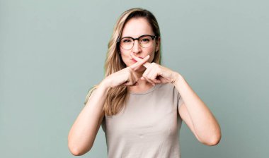 Ciddi ve hoşnutsuz görünüyor. İki parmağın önde olsun, reddedilmek üzere, sessizlik istiyorsun.