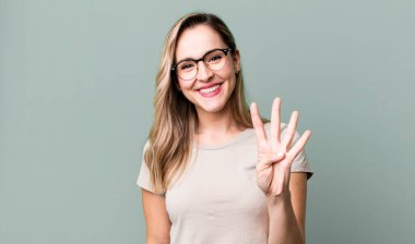 Gülümsüyor ve dost canlısı görünüyor, 4 ya da 4 numarayı gösteriyor, elle ileri doğru, geri sayıyor.