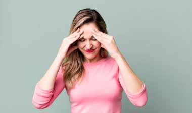 Stresli ve hayal kırıklığına uğramış görünüyor, baskı altında çalışıyor, baş ağrısı ve sorunlarla boğuşuyor.