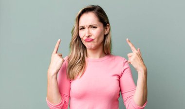 Kibirli ve agresif görünen, yukarıyı gösteren ya da ellerinle alay eden bir tavır takınarak.