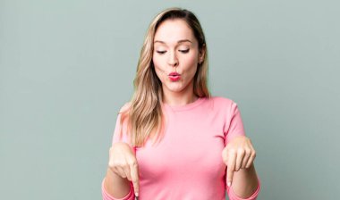 İki eliyle aşağıya doğru bakan ağzı açık, şaşkın, şaşkın ve şaşırmış bir şekilde bakan