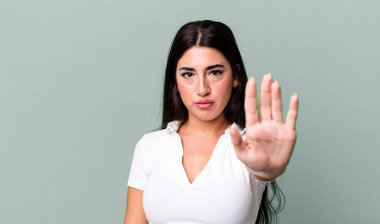 Ciddi, sert, hoşnutsuz ve kızgın görünüyor. Avuç içini açıp, jestleri durduruyor.