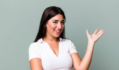 Gururla ve özgüvenle gülümseyen, mutlu ve tatmin olmuş hisseden ve fotokopi alanında bir konsept gösteren