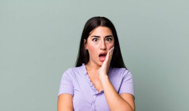 Şok ve inançsızlıkla ağzı açık, elleri yanakları ve kolları çaprazlanmış, sersemlemiş ve şaşkın.