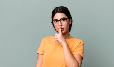 Ciddi görünüyor ve parmaklarını dudaklarına bastırıyor sessizlik ya da sessizlik talep ediyor, sır saklıyor.