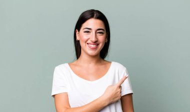 Neşeli bir şekilde gülümseyen, mutlu hisseden, kenarı ve yukarıyı gösteren, kopya uzayda nesneleri gösteren