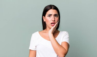 Şok ve inançsızlıkla ağzı açık, elleri yanakları ve kolları çaprazlanmış, sersemlemiş ve şaşkın.