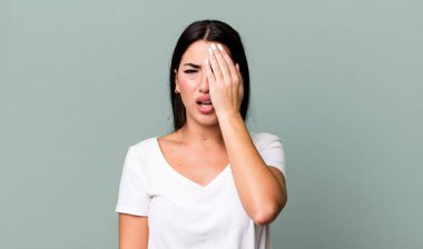 Uykulu görünüyor, sıkılmış ve esniyor, baş ağrısı ve yüzünün yarısını kaplayan bir elle.