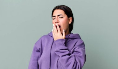 Sabahın köründe tembelce esniyor, uykulu, yorgun ve sıkkın görünüyor.