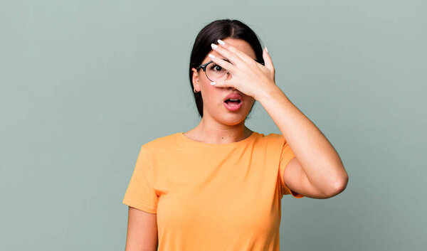 в шоке, испуге или ужасе, закрывая лицо рукой и подглядывая между пальцами