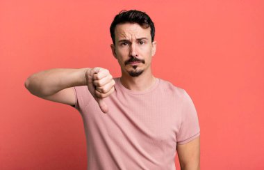 Kızgın, sinirli, hayal kırıklığına uğramış ya da hoşnutsuz, ciddi bir bakışla başparmaklarını aşağı gösteren.