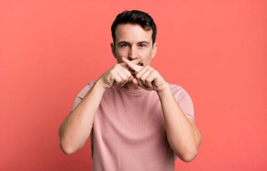 Ciddi ve hoşnutsuz görünüyor. İki parmağın önde olsun, reddedilmek üzere, sessizlik istiyorsun.