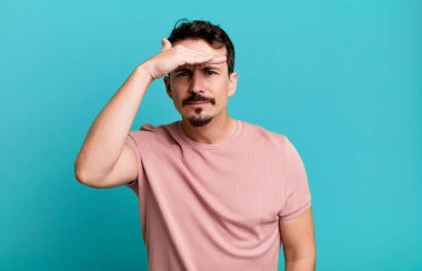 Afallamış ve şaşkın bir halde, el üstünde, uzaklara bakıyor, izliyor ya da arıyor.