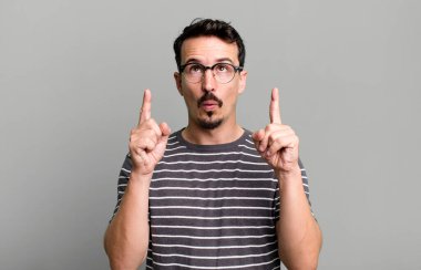 Şaşırmış, şaşırmış ve ağzı açık bir şekilde iki eliyle uzayı kopyalamak için yukarı bakıyor.