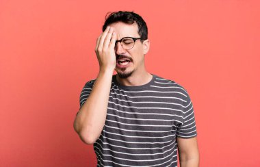 Uykulu görünüyor, sıkılmış ve esniyor, baş ağrısı ve yüzünün yarısını kaplayan bir elle.