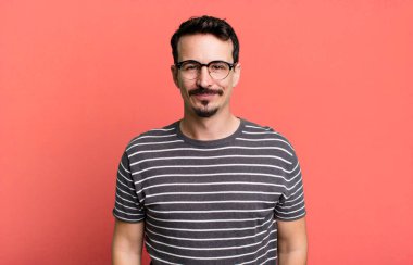 Olumlu ve kendinden emin gülümsüyor, tatmin olmuş, arkadaş canlısı ve mutlu görünüyor.