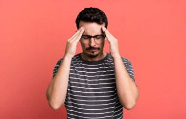 Stresli ve hayal kırıklığına uğramış görünüyor, baskı altında çalışıyor, baş ağrısı ve sorunlarla boğuşuyor.