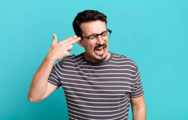 Mutsuz ve stresli görünüyor, intihar jesti elle silah işareti yapıyor, kafasını işaret ediyor.